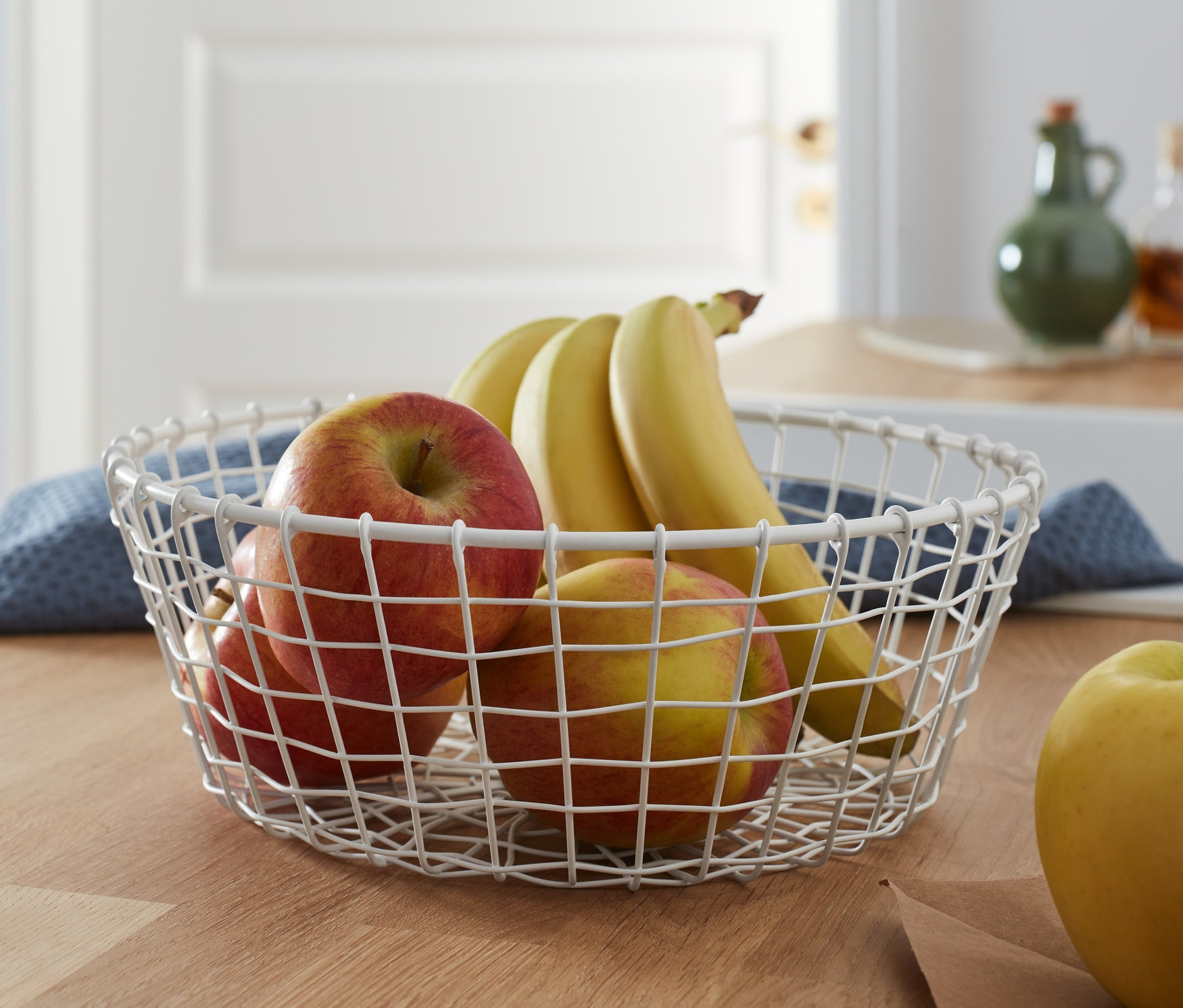 Äpfel und Bananen in einer Drahtschale.