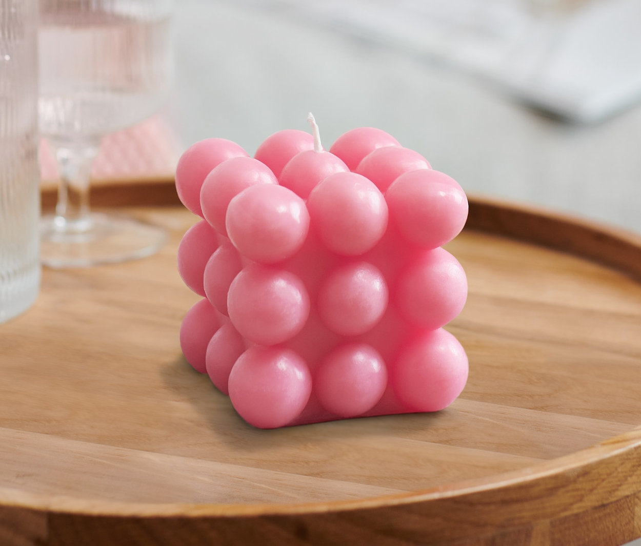 Auf einem Holztisch stehen 2 Bubble-Kerzen, ein Glas Wasser und eine Karaffe.