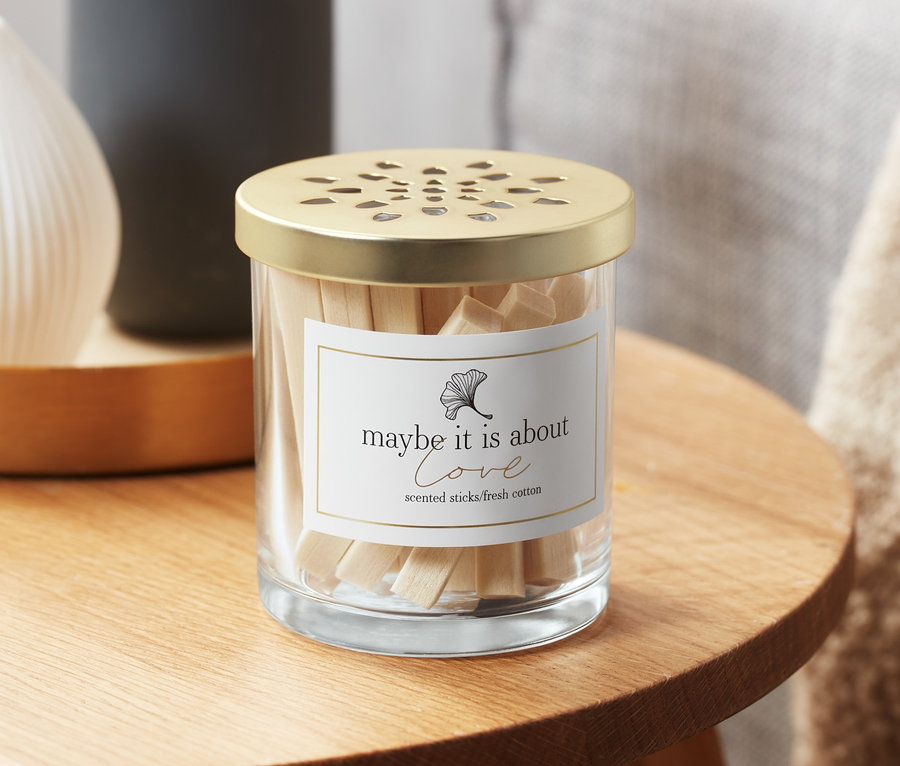 Glasbehälter mit Raumduft-Sticks, Baumwollfelder, auf einem Holztisch.