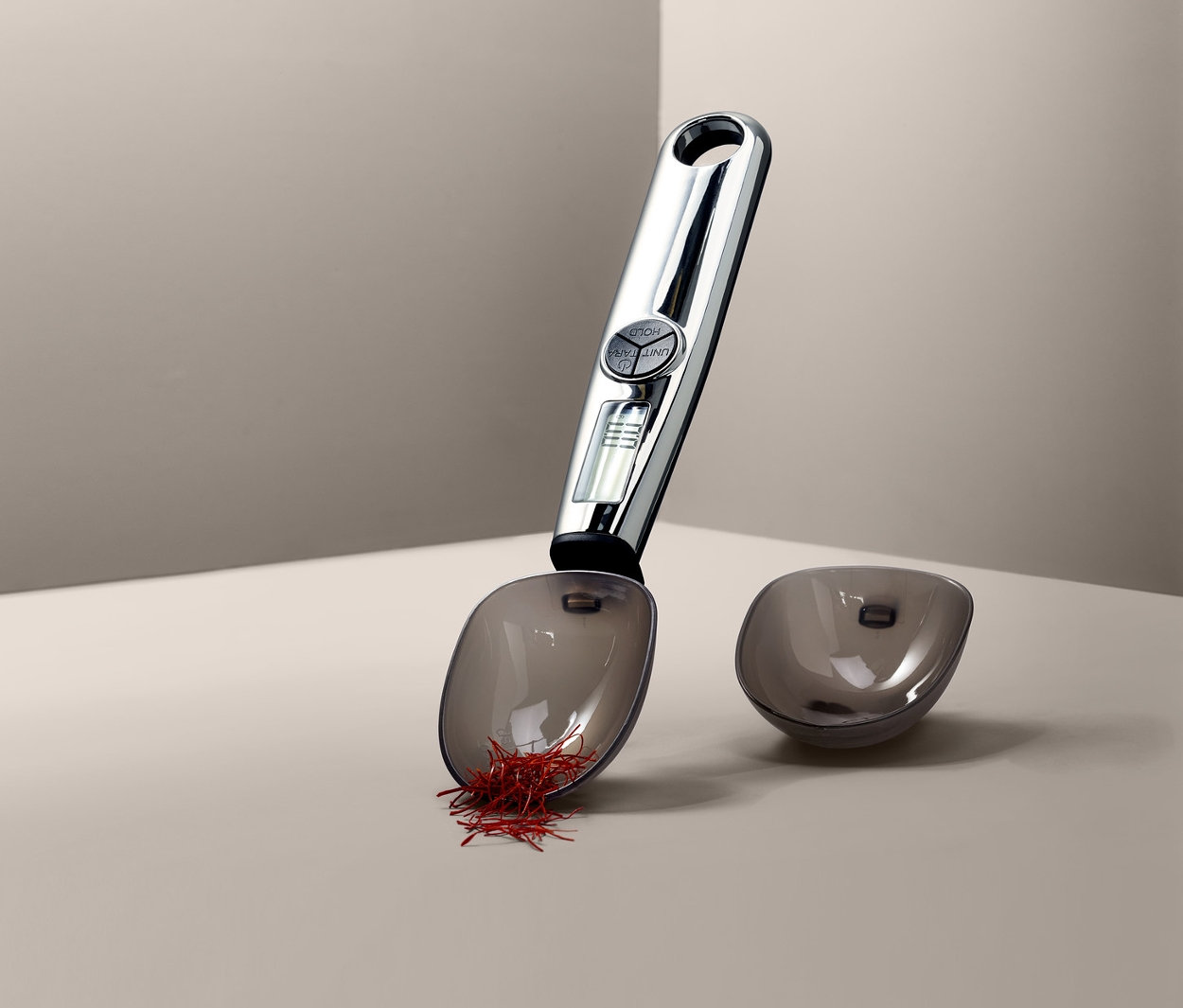 Digitale Löffelwaage mit Safran und leerem Behälter.