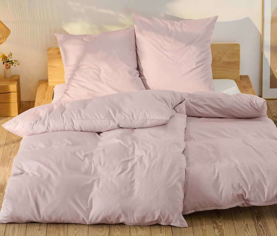 Rosafarbene Baumwollsatin-Bettwäsche in Normalgröße und Übergröße auf einem Bett.