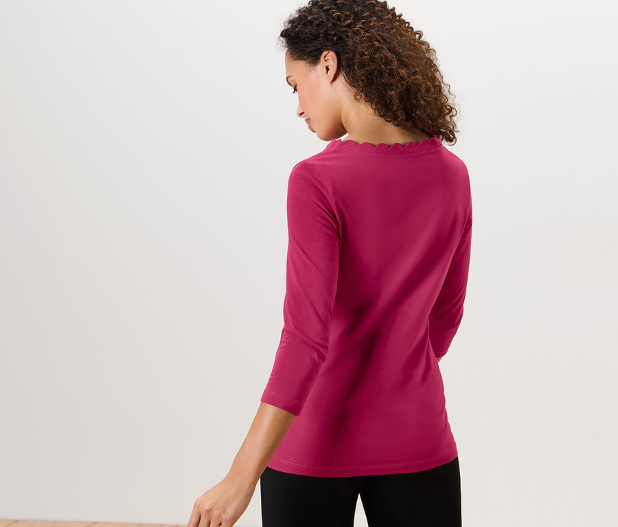 Frau trägt ein himbeerrotes Shirt mit 3/4-Arm.