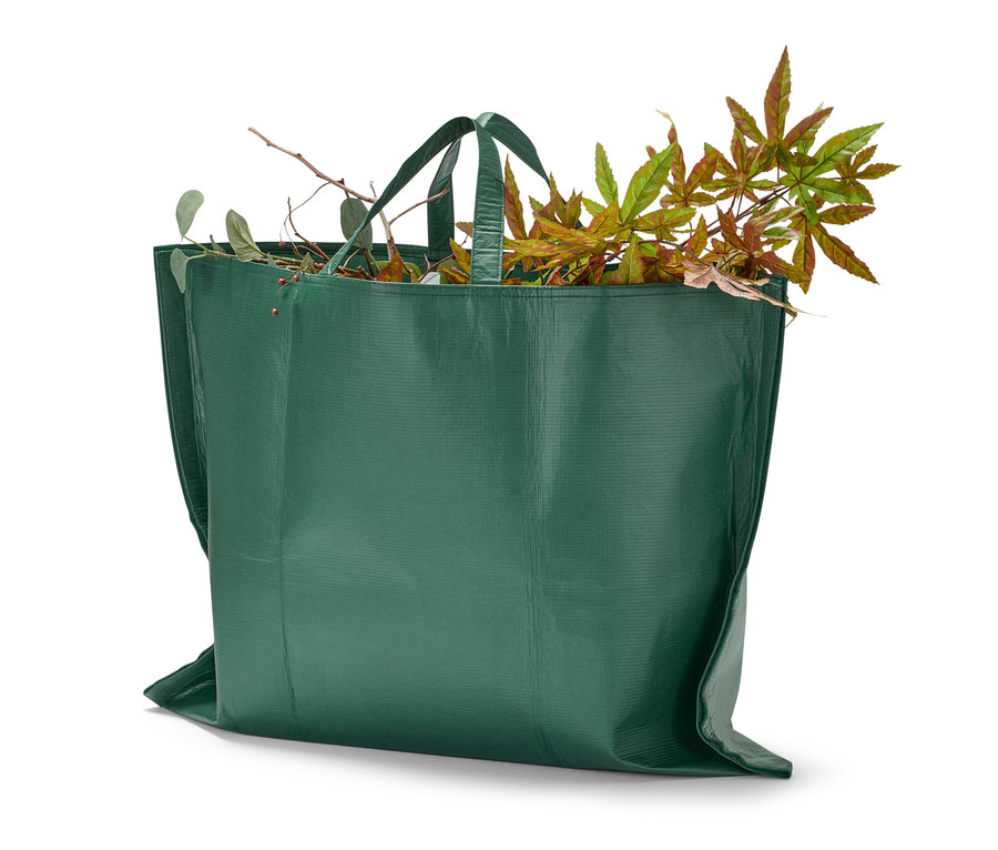 Eine grüne Gartenabfalltasche gefüllt mit Blättern und Ästen.