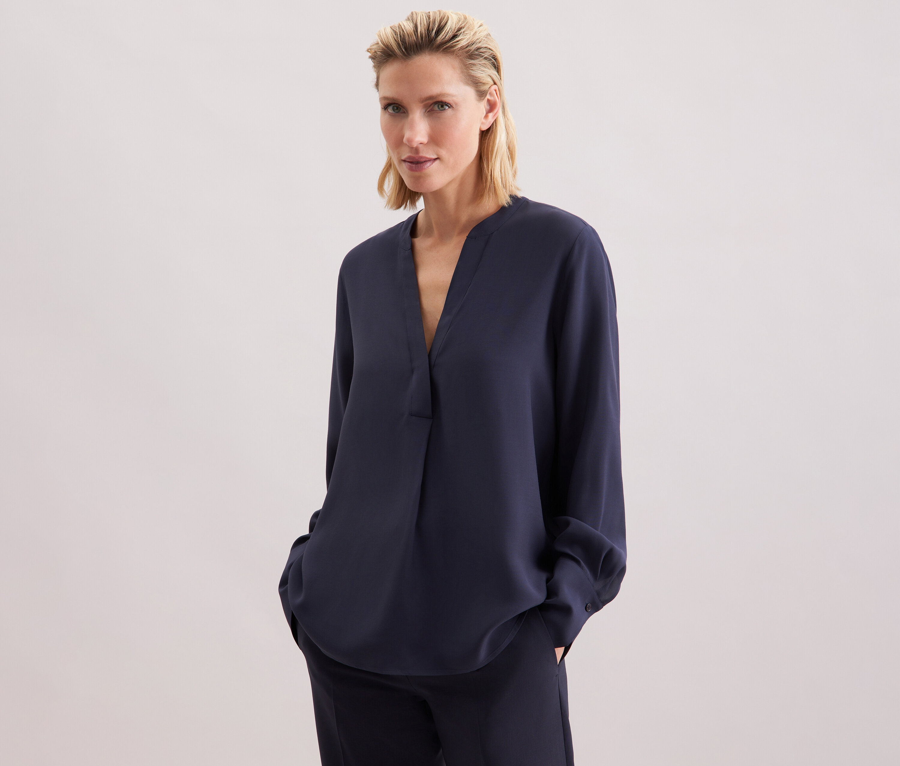 Frau trägt eine marineblaue Seidensticker Tunika aus Viskose und eine Hose.