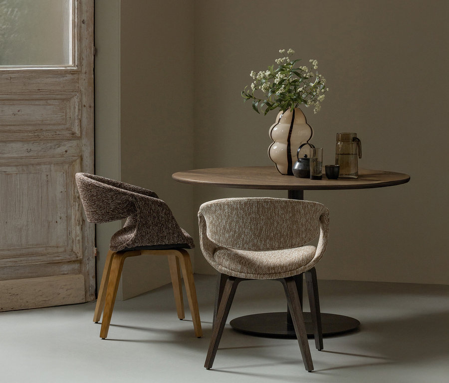 Zwei braune WOOOD Esszimmerstühle »Yossi« mit naturfarbenem Holzfuß aus einem 2er-Set stehen an einem Holztisch. Auf dem Tisch stehen eine Vase mit Blumen, eine Teekanne, ein Glas und ein Krug.