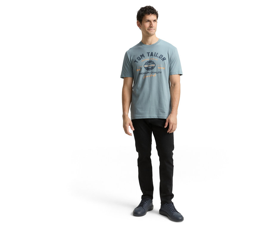 Mann in schwarzer Hose, mit Tom Tailor T-Shirt mit Logo in Grey Mint.