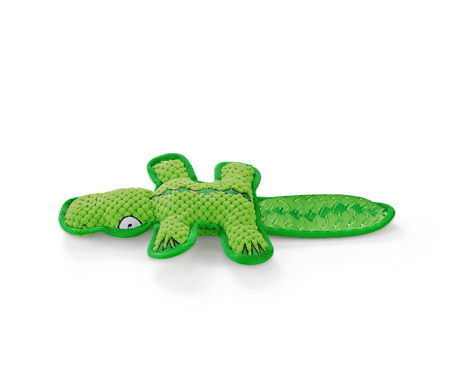 Ein grünes Hunde-Plüschspielzeug in Krokodilform liegt auf einem weißen Hintergrund.