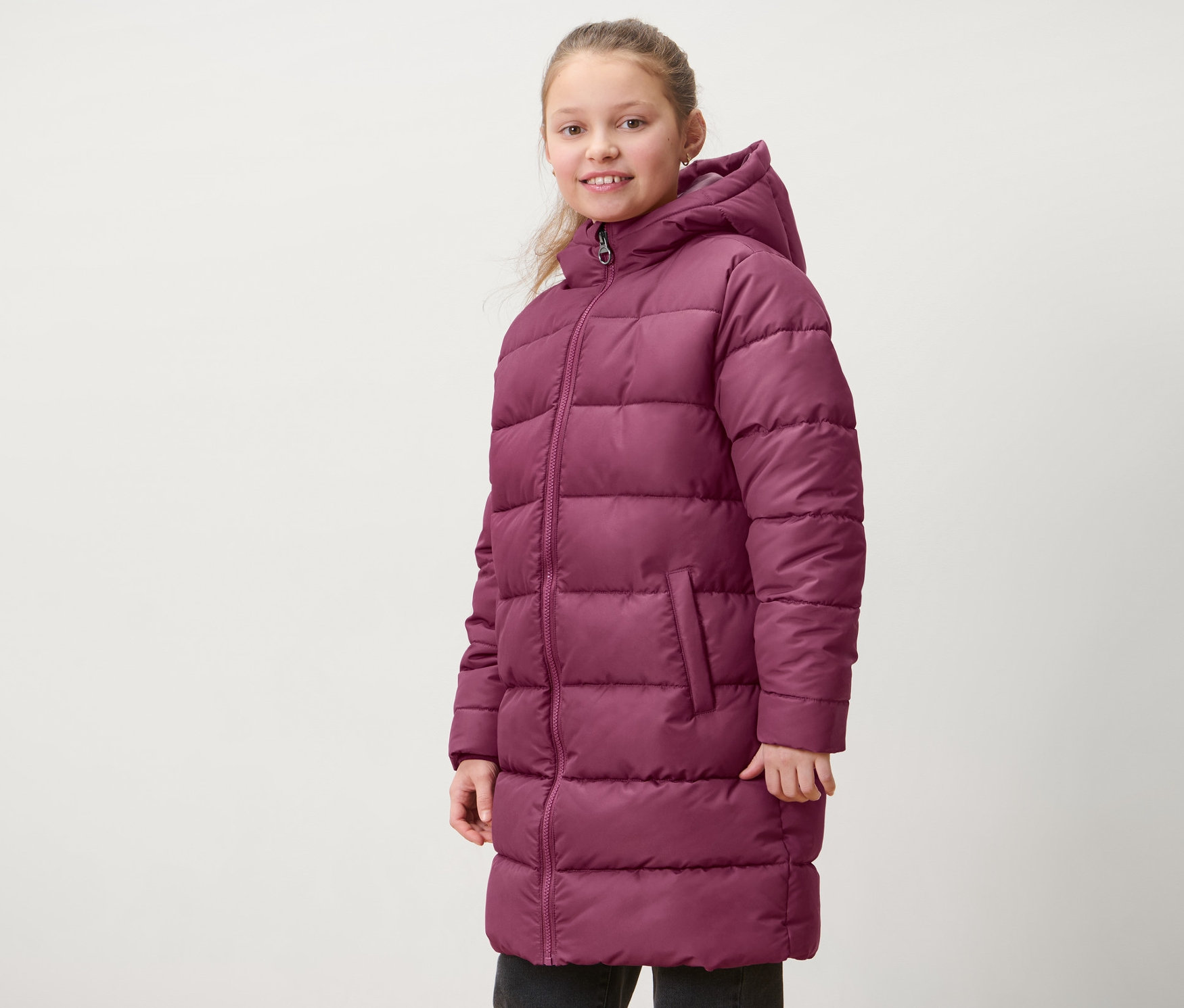 Mädchen trägt einen rotvioletten Kinder-Thermomantel.