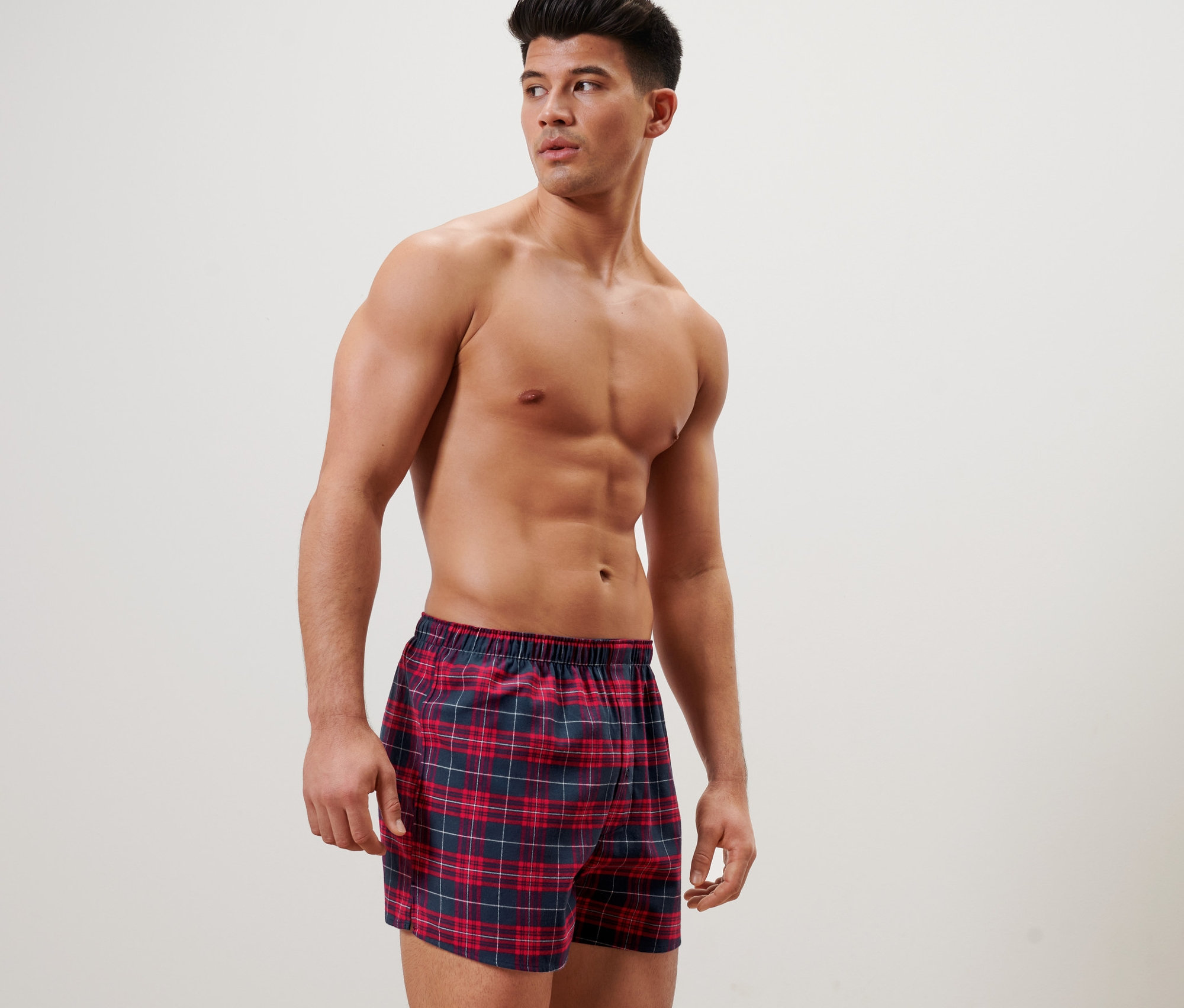 Mann posiert in karierten Flanell-Boxershorts.