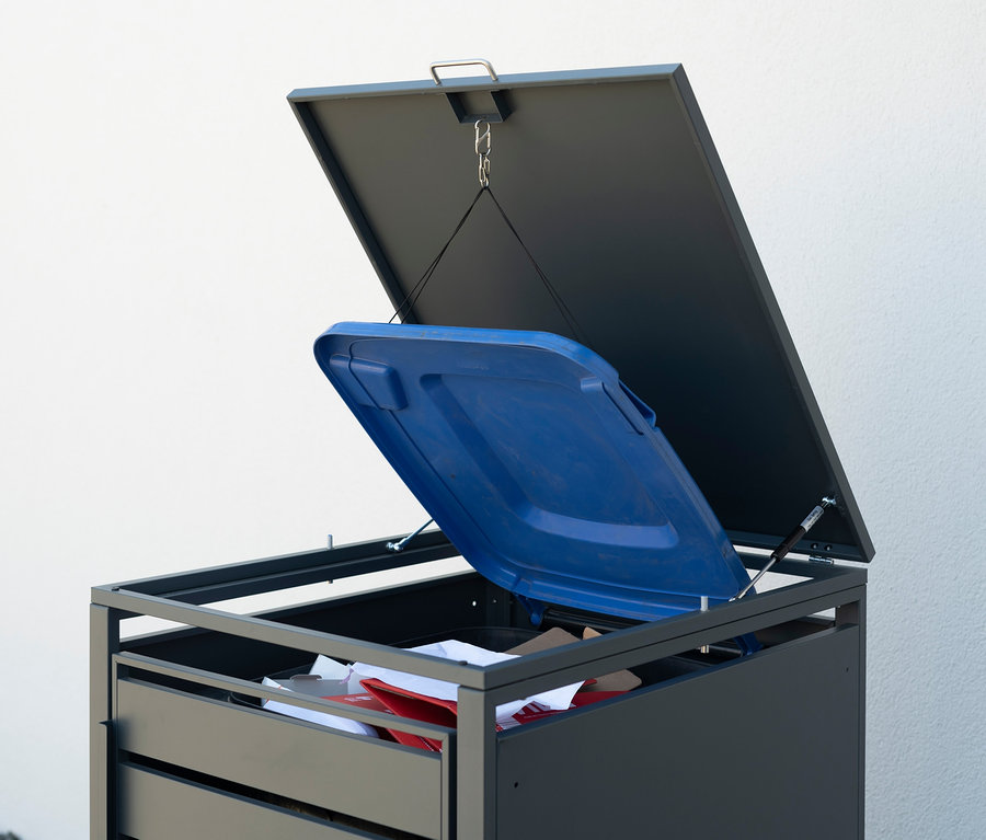 Geöffneter Mülltonnenbox aus Stahl mit blauem Deckel und Abfall darin.