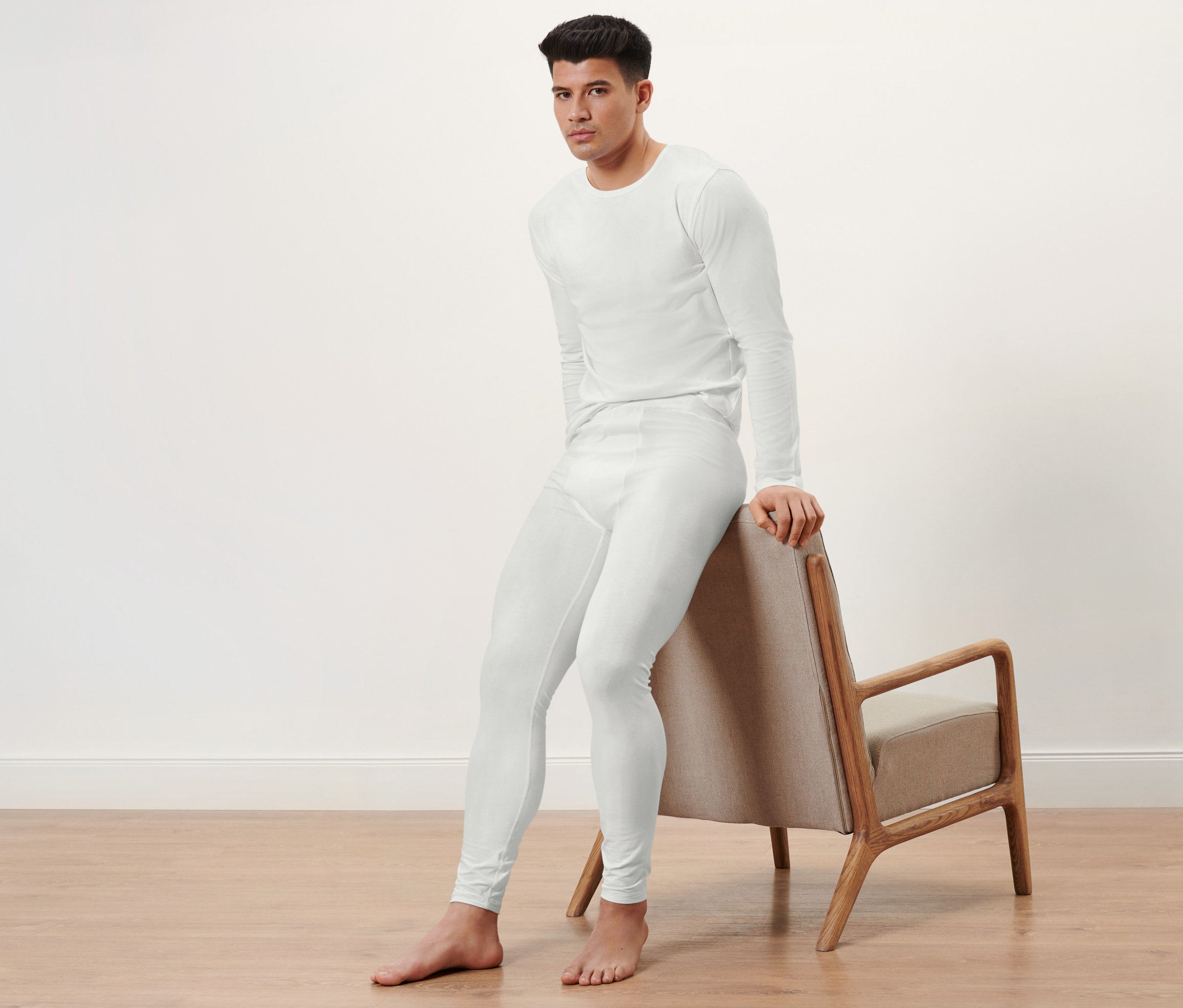 Mann sitzt auf einem Stuhl und trägt 2 lange Unterhosen.