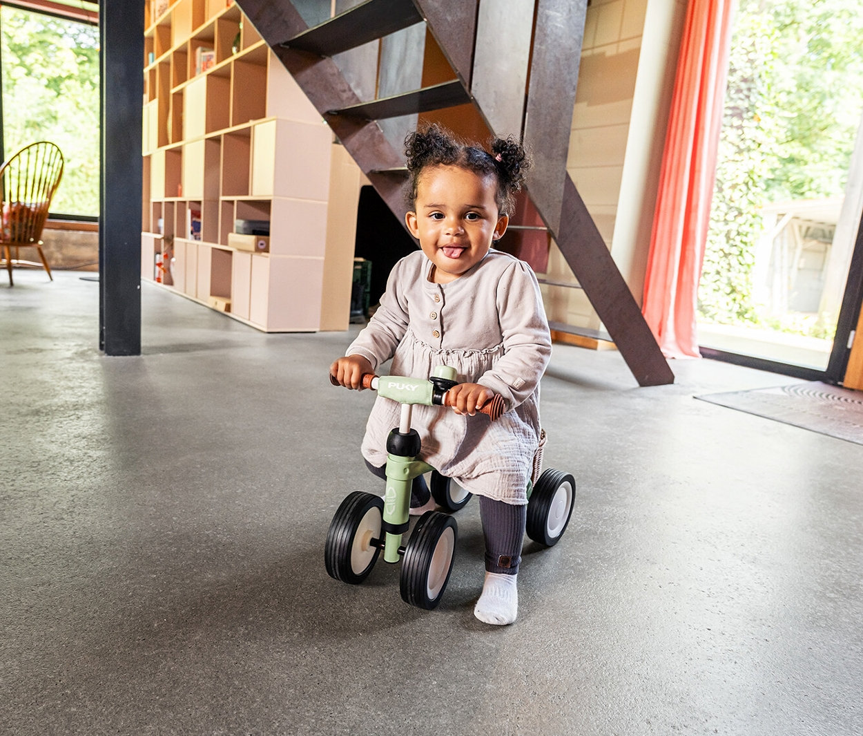 Ein Kind fährt mit einem PUKY Laufrad PUKYLINO BUNDLE in einem Wohnzimmer.