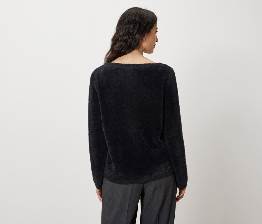 Rückansicht einer Frau mit schwarzem Pullover und grauer Hose.