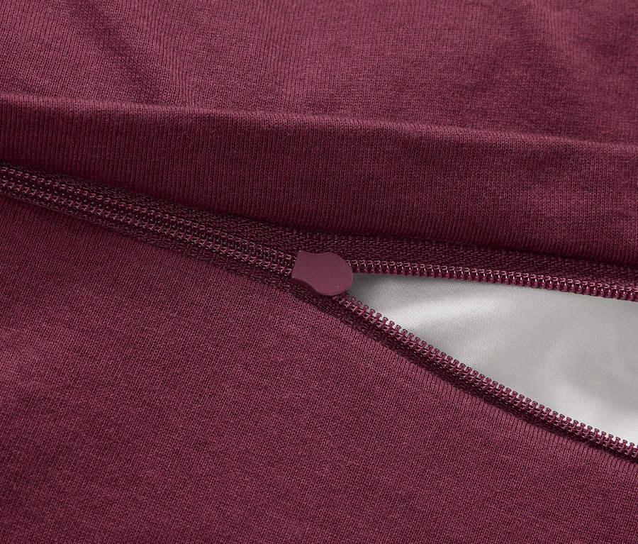 Detailaufnahme eines bordeauxroten Reißverschlusses auf Stoff.