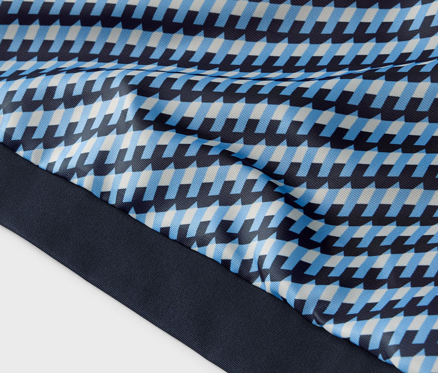 Nahaufnahme eines Stoffes mit blauem, hellblauem und weißem geometrischen Muster und dunkelblauem Saum.