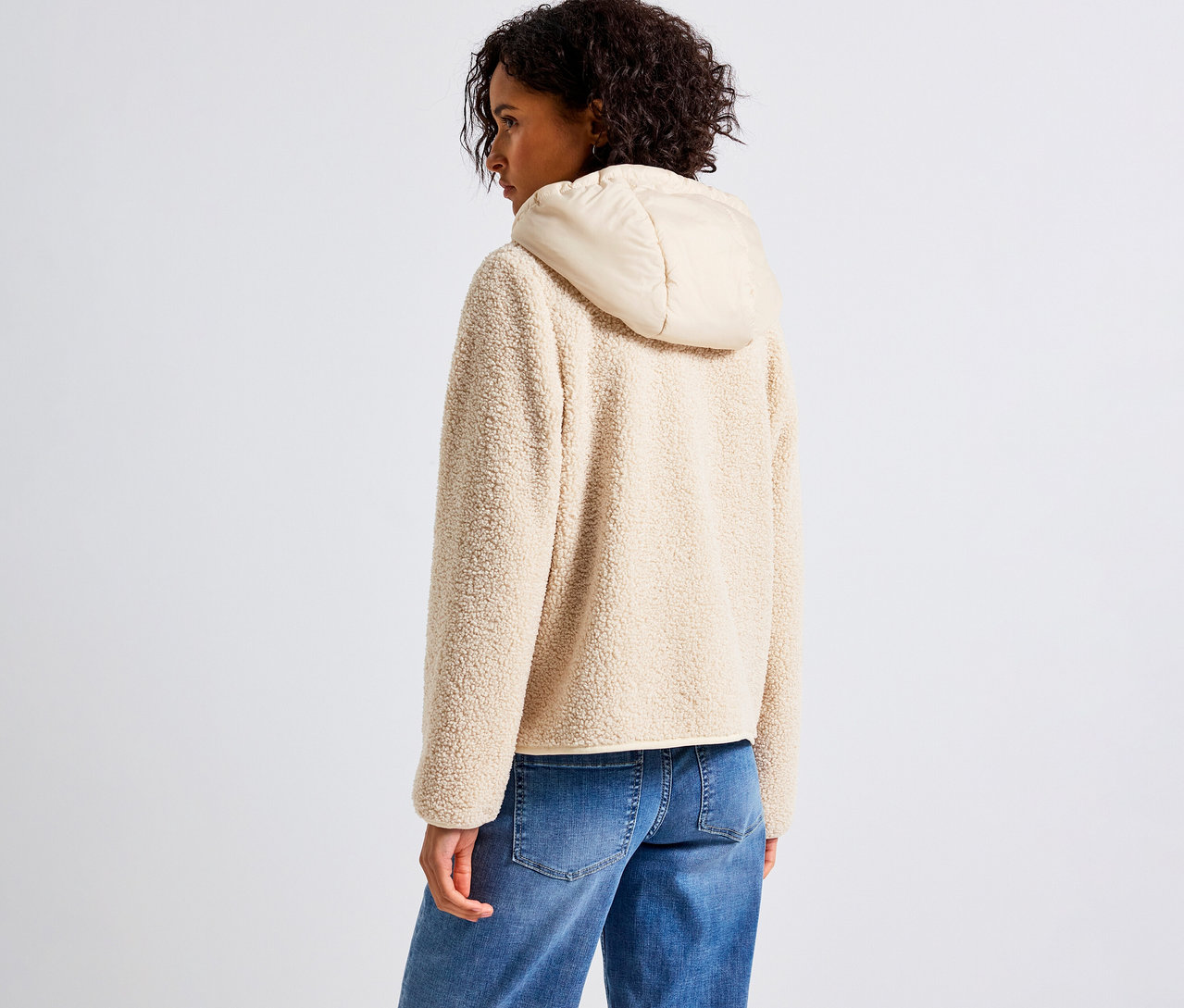 Frau trägt eine beige Street One Teddyjacke mit abnehmbarer Kapuze, kombiniert mit blauen Jeans.