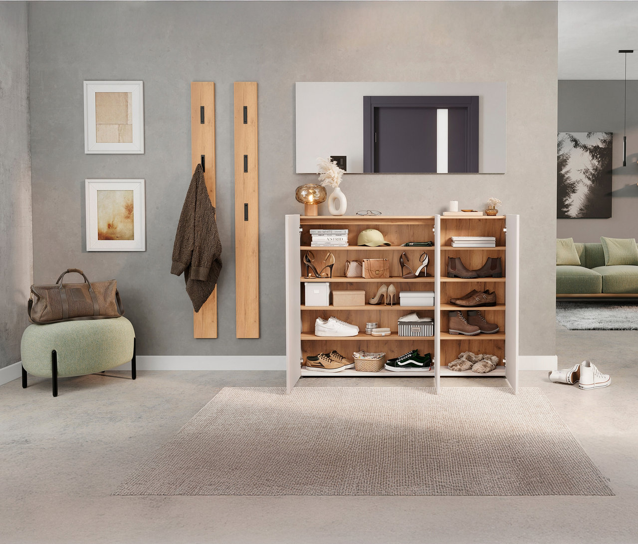 Eingangsbereich mit offenem Schuhschrank, auf dem Accessoires stehen. An der Wand hängen eine Garderobe, ein Spiegel und zwei Bilder.