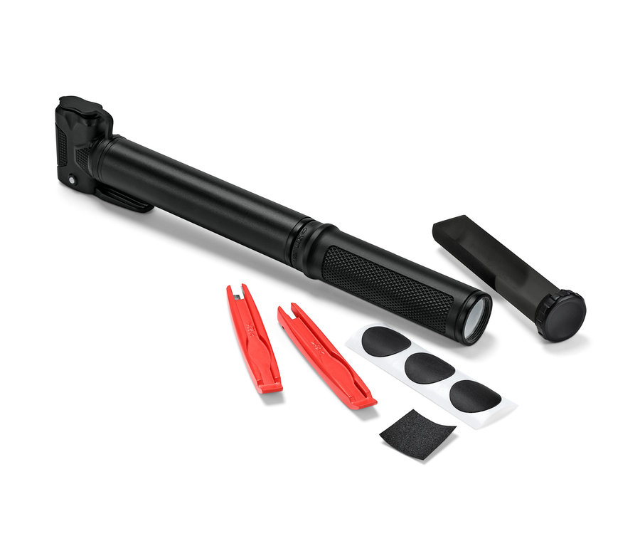 Eine schwarze Mini-Fahrradpumpe liegt neben zwei roten Reifenhebern, Flicken und Schmirgelpapier.