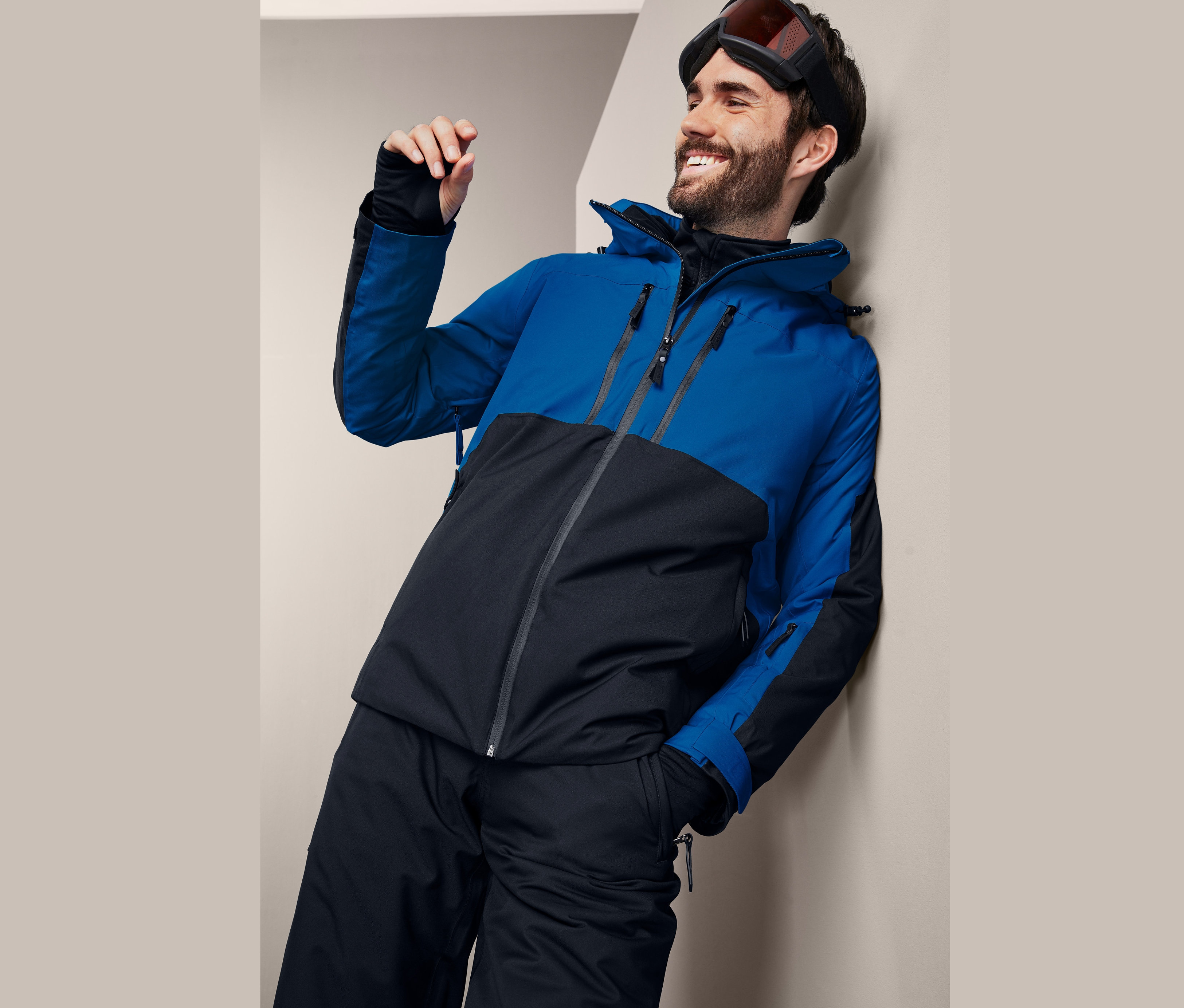 Mann mit Skijacke lehnt an der Wand.