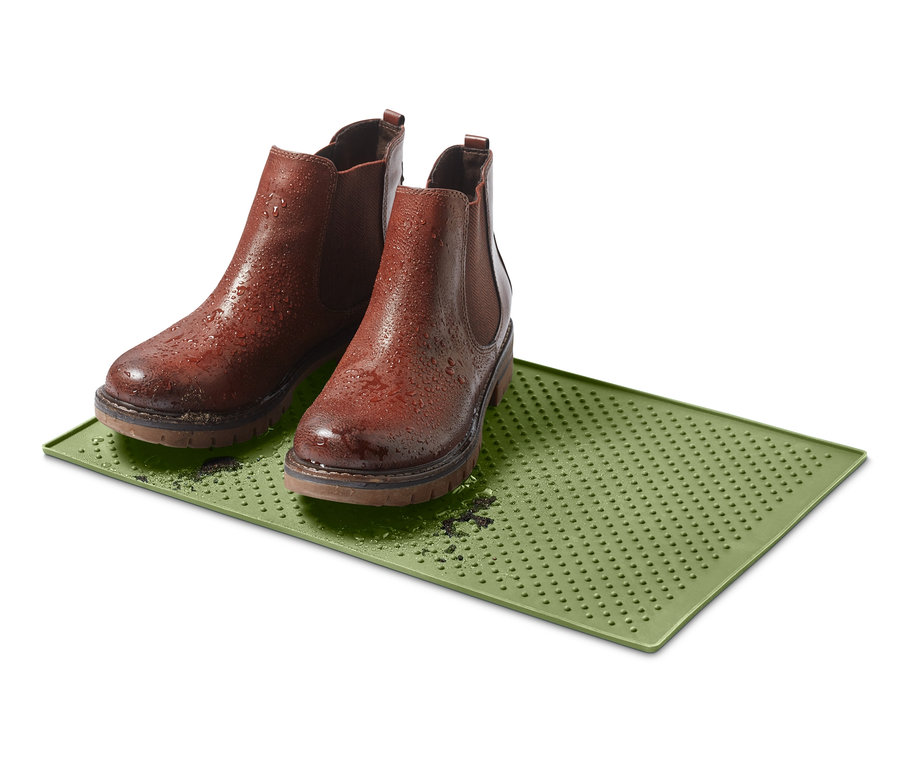 Zwei braune Stiefel stehen auf einem grünen Futternapf-Untersetzer.