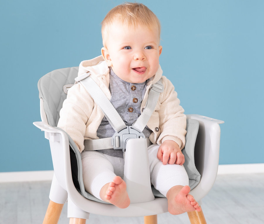 Ein Kind sitzt im grauen roba 2-in-1-Hochstuhl »Style Up wood« mit Holzbeinen.