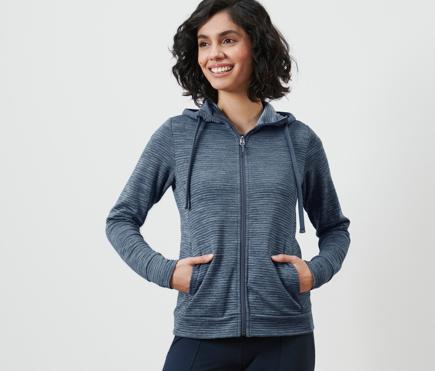 Frau posiert in dunkelblauer Kapuzenjacke.