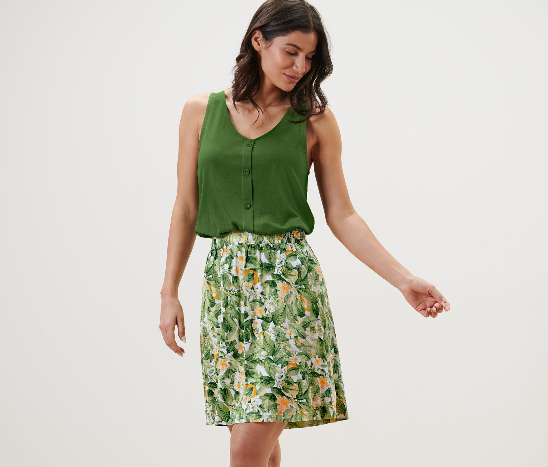 Frau trägt ein grünes Top und einen bedruckten Jerseyrock.