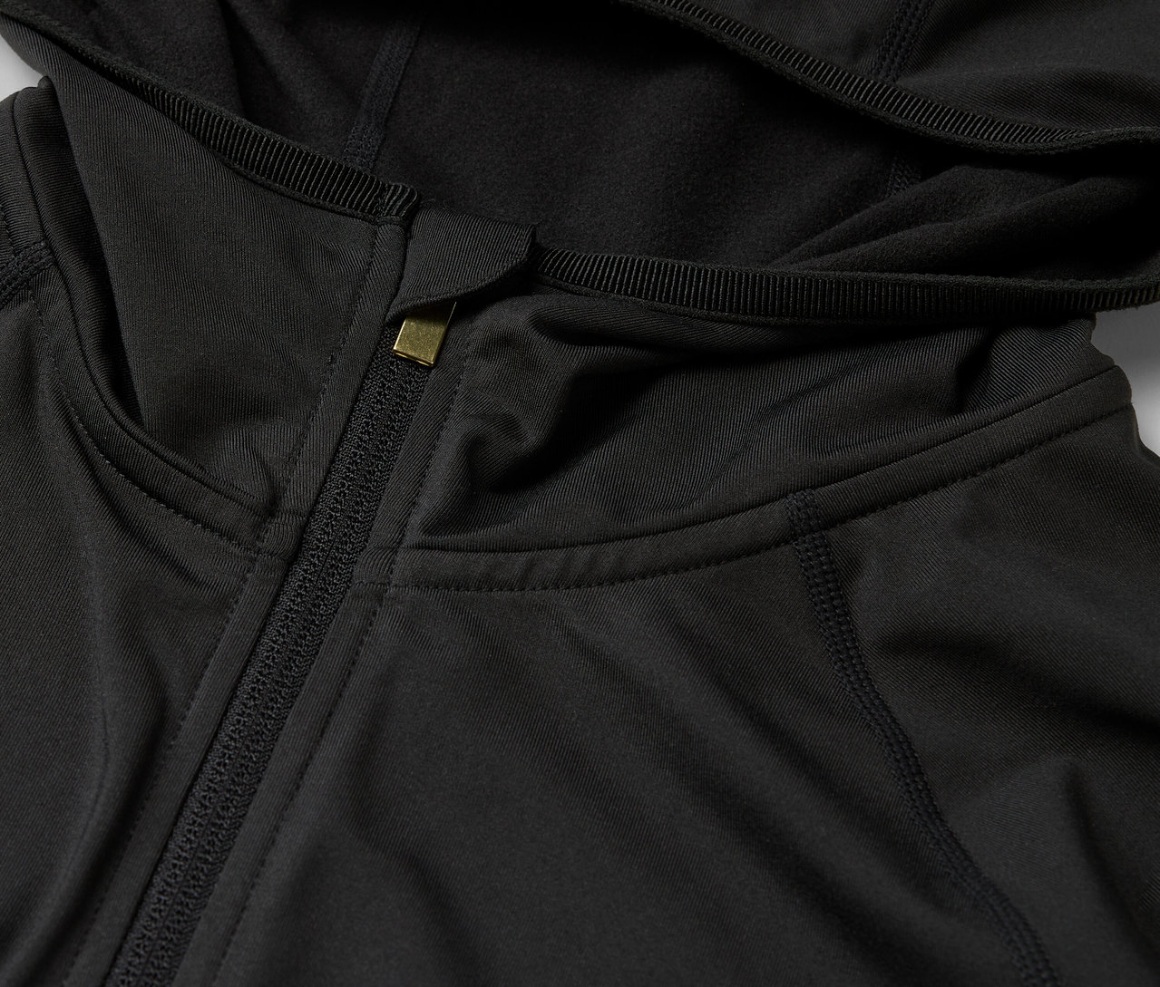 Detailaufnahme einer schwarzen Kapuzenjacke mit Reißverschluss.