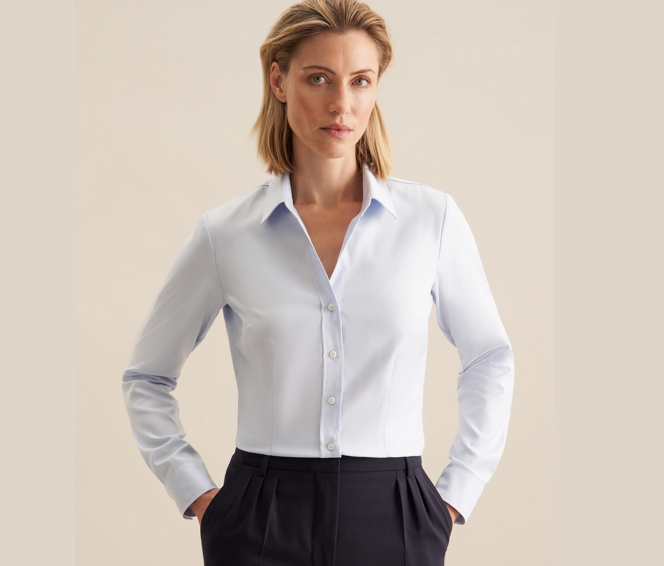 Frau trägt eine hellblaue Seidensticker Twillbluse und eine dunkelblaue Hose.