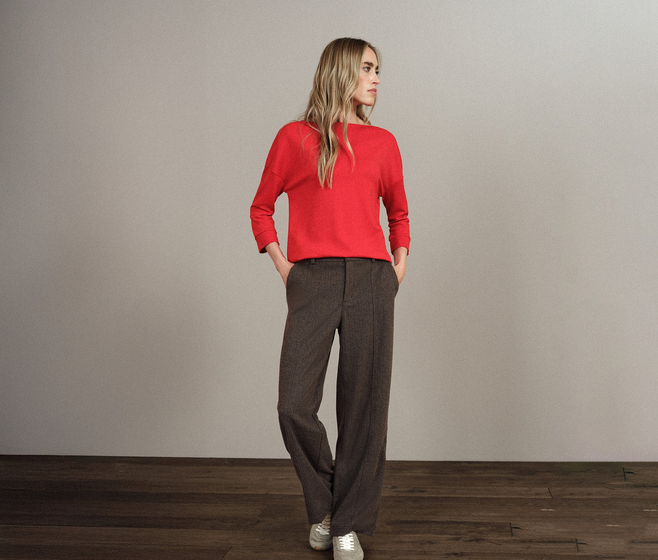 Eine blonde Frau steht mit den Händen in den Taschen ihrer Street One Hose Straight Leg.