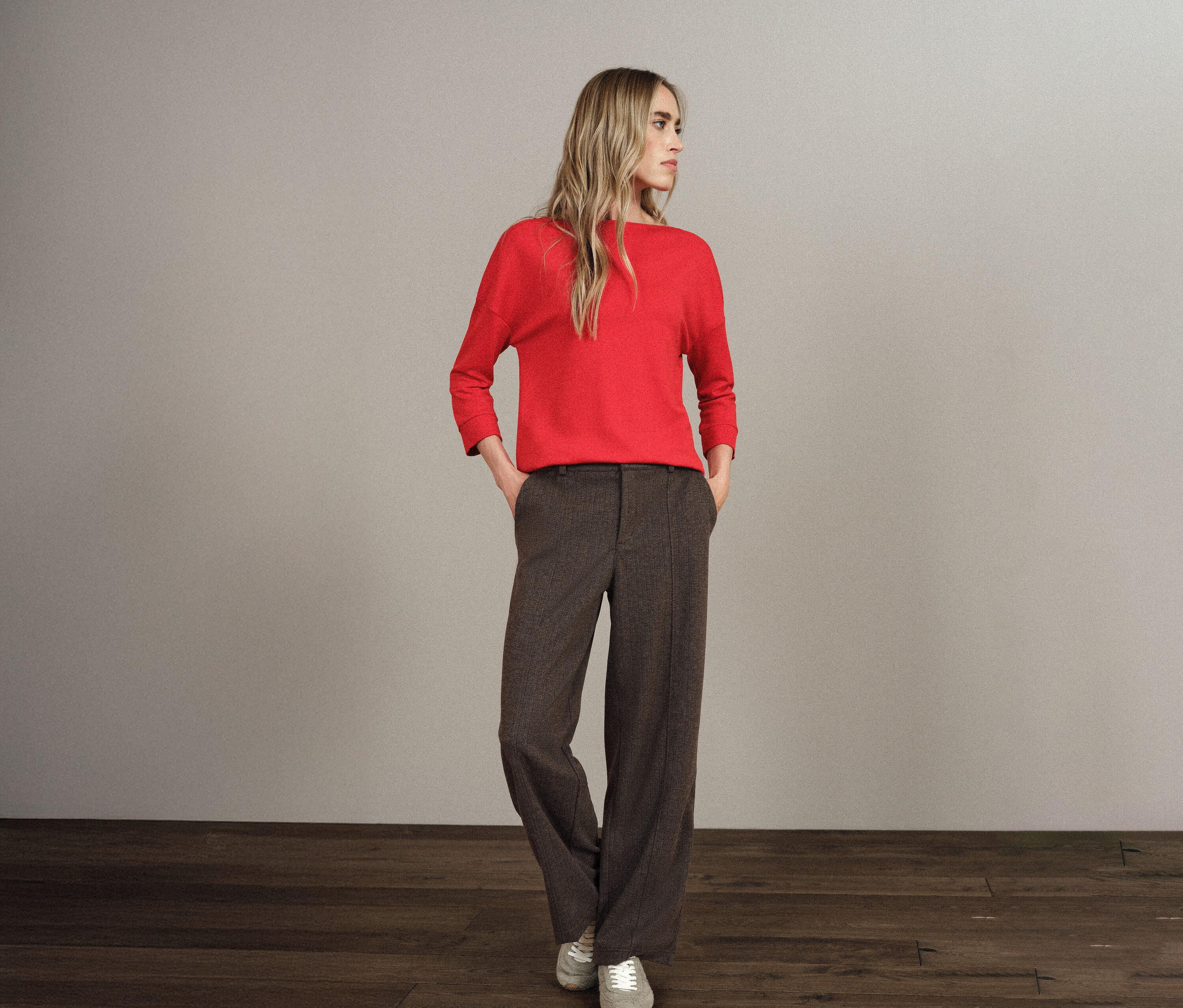 Eine blonde Frau steht mit den Händen in den Taschen ihrer Street One Hose Straight Leg.