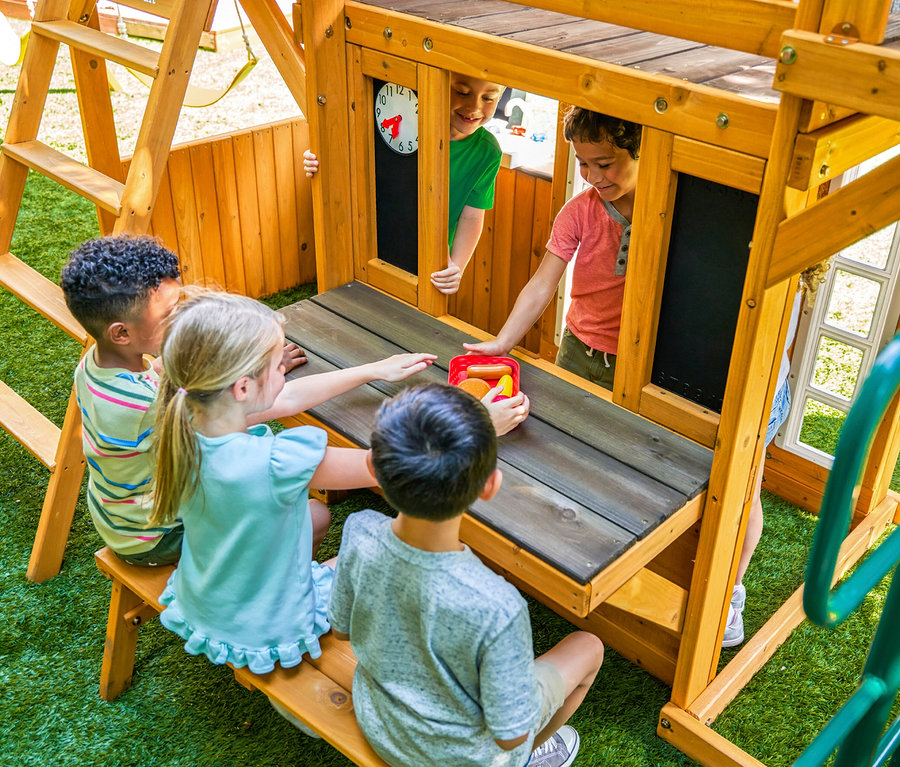 Fünf Kinder spielen im Freien am Spielturm »Bolzo« aus Holz.