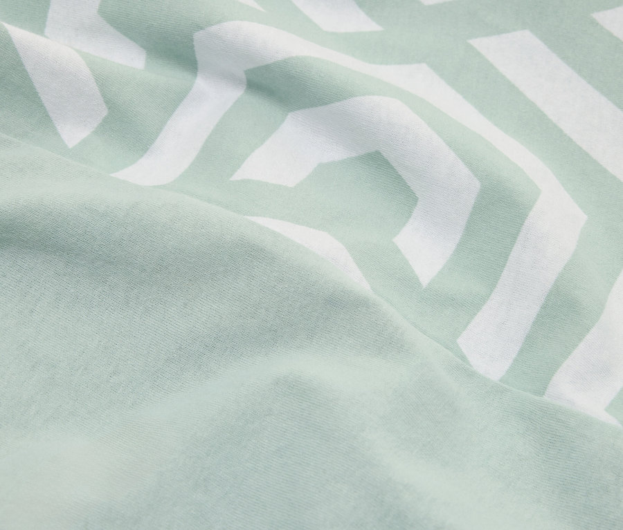 Nahaufnahme eines mintgrünen Stoffes mit weißem Zickzackmuster.