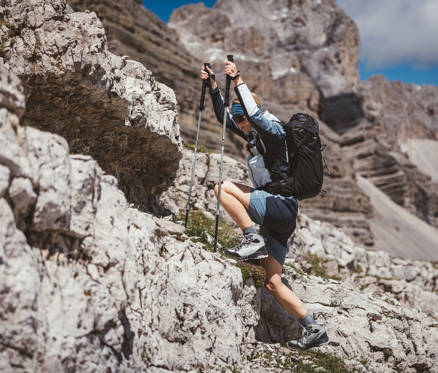 Frau klettert mit CMP Trekking-Stöcken einen Felsen hoch, mit CMP Trekking-Rucksack HAVRE, 40 Liter.