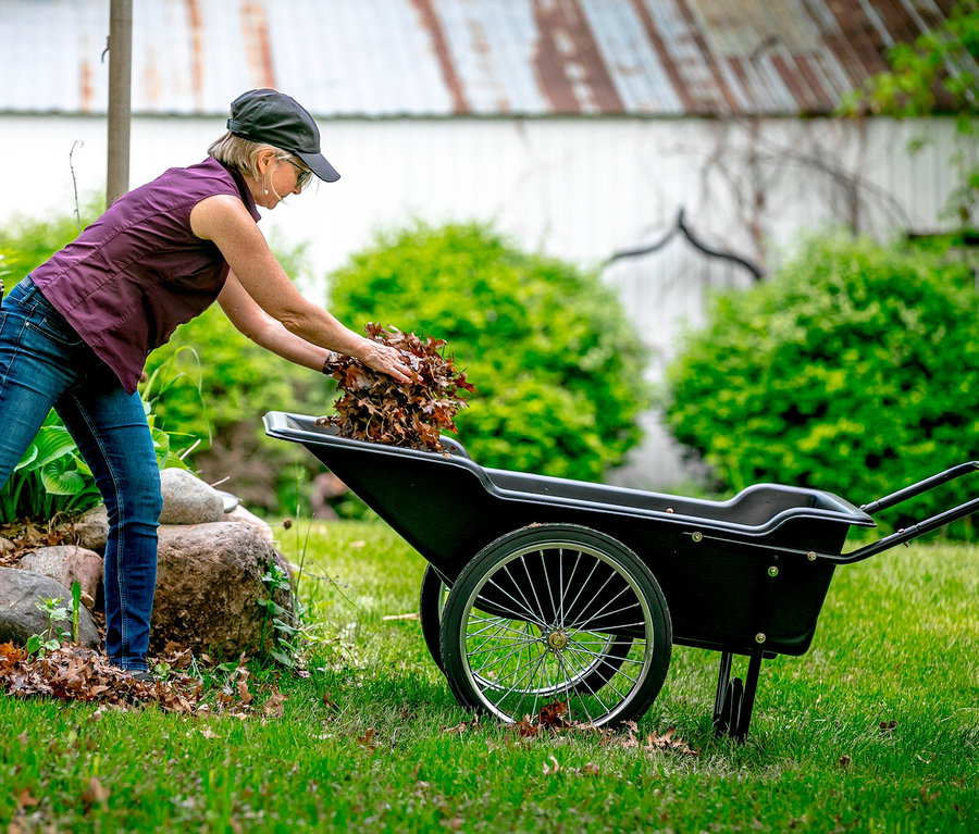 Frau lädt Laub in eine schwarze Polar Schubkarre »Premium«.