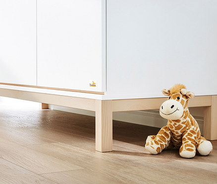 Ein weißes und hölzernes 3-teiliges Pinolino Set "Light" mit einer Plüschgiraffe und einem gelben Kissen.