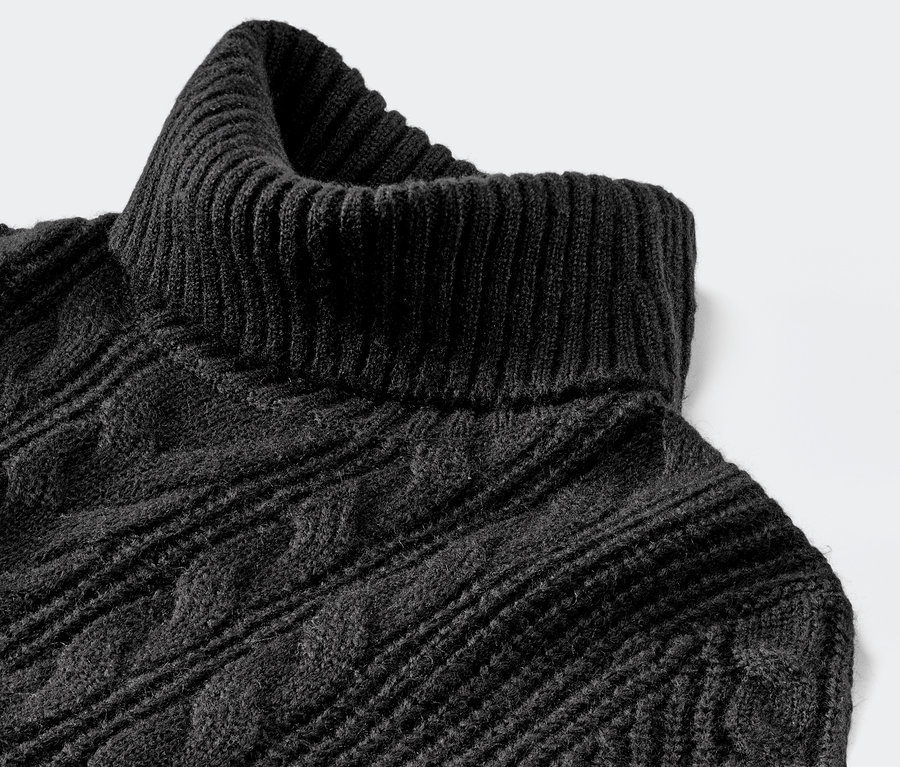 Detailaufnahme eines schwarzen, langen Strickpullovers mit Zopfmuster.