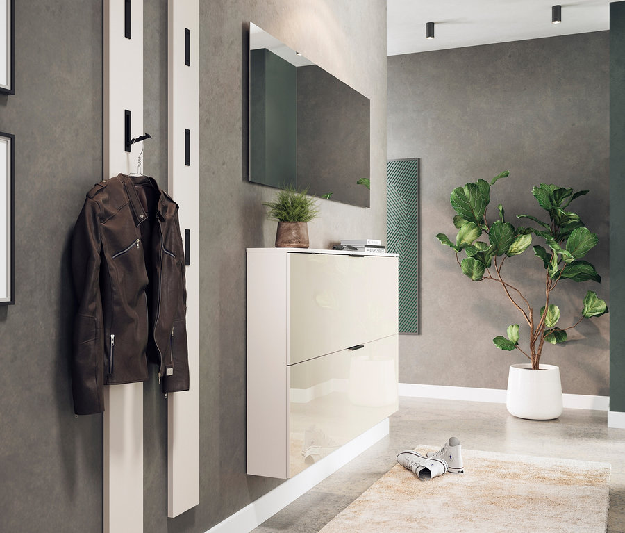 Eine braune Jacke hängt an einer weißen Garderobe neben einem beigen Schuhschrank »Valega« mit Spiegel darüber.