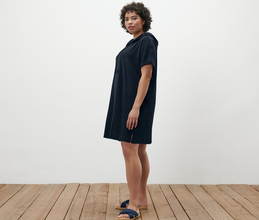 Frau posiert in blauem Frottee-Strandkleid.