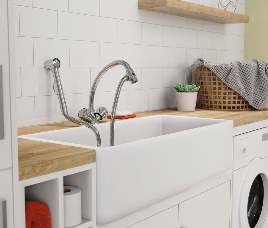 Innenaufnahme eines Waschraums mit einem weißen Keramikspülbecken, einer Chromarmatur und einer Waschmaschine.