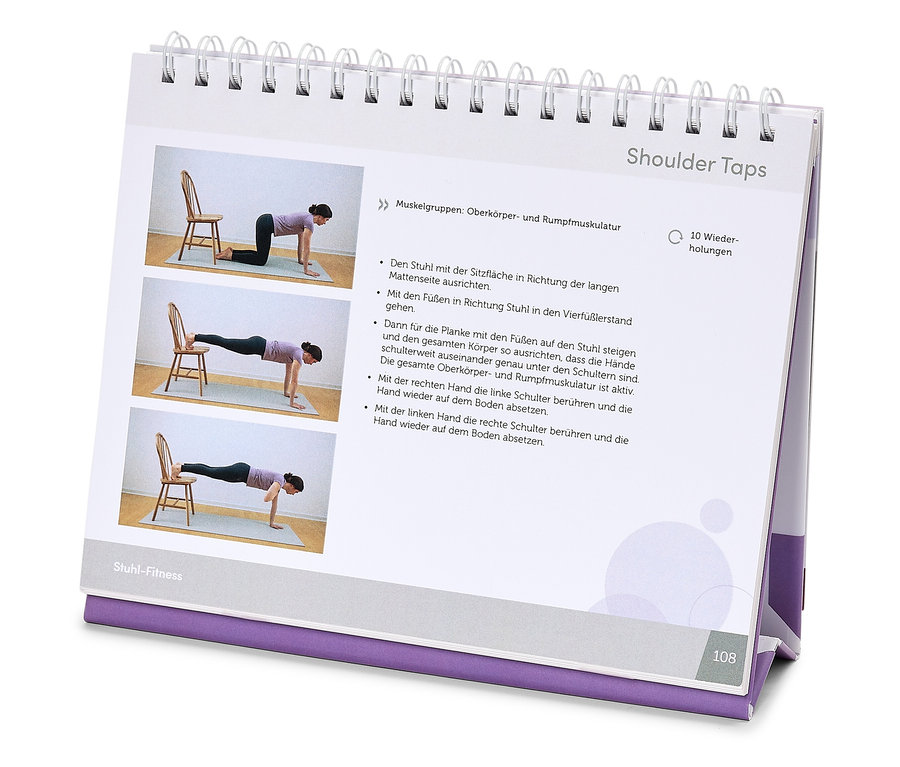 Offenes Fitness-Handbuch zeigt eine Frau, die Shoulder Taps mit einem Stuhl auf einer Matte vorführt.