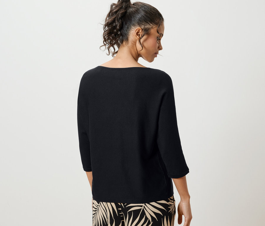 Frau von hinten trägt einen schwarzen Feinstrickpullover.