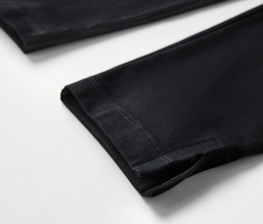 Detailaufnahme einer schwarzen 3/4-Leggings mit Saum auf weißem Hintergrund.