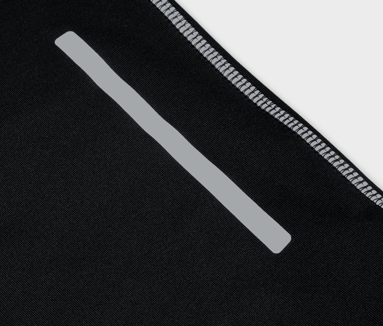 Detailaufnahme von schwarzer Sportbekleidung mit reflektierendem Streifen und grauem Saum.