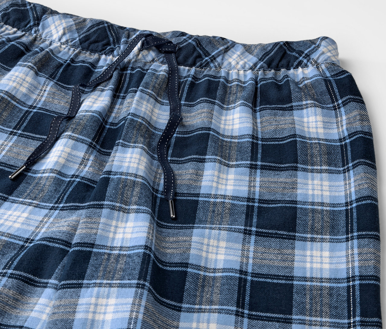 Detailaufnahme einer blau karierten Flanellhose mit elastischem Bund und Kordelzug.