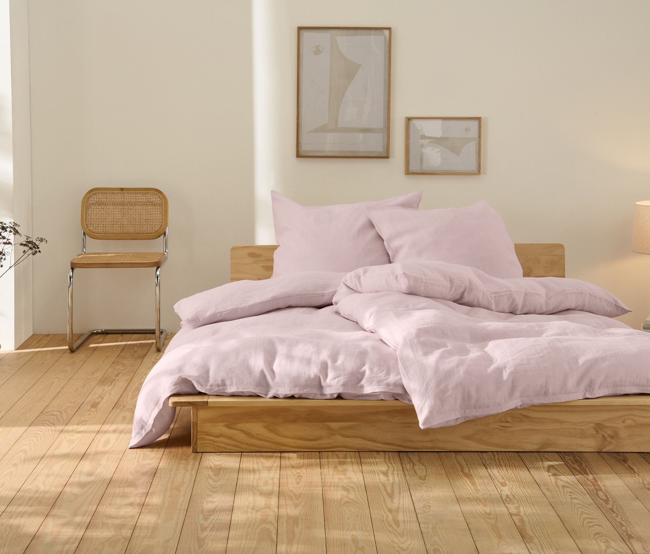 Rosafarbene Leinen-Bettwäsche in Übergröße liegt auf einem Holzbett.