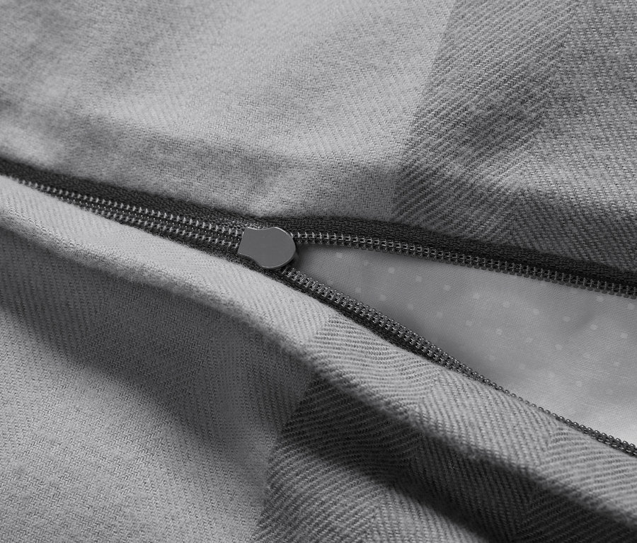 Detailaufnahme eines grauen Bettbezugs mit geöffnetem Reißverschluss.