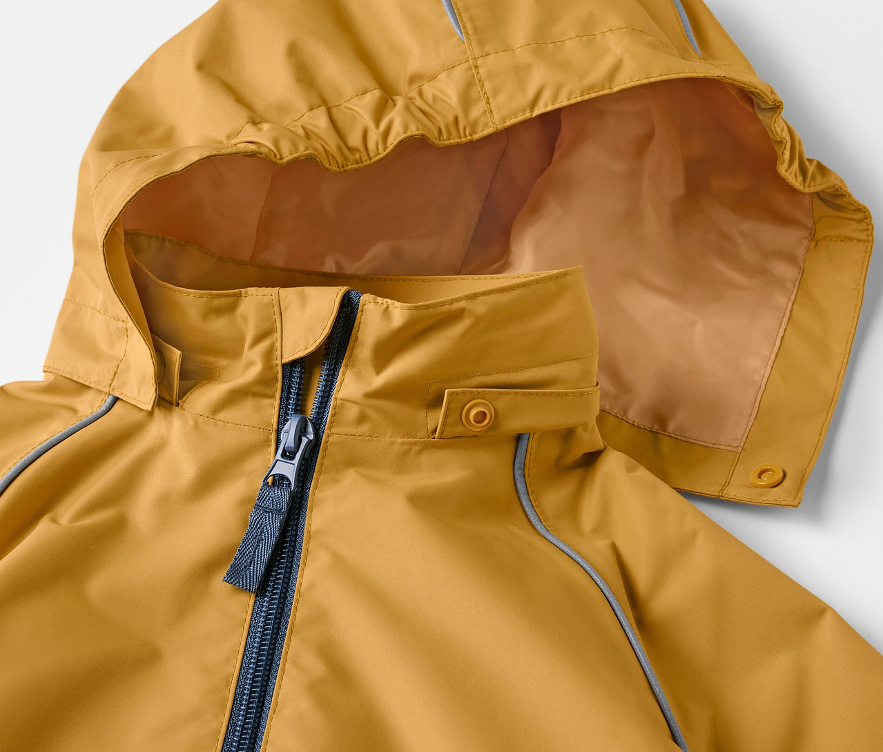 Detailansicht einer ockerfarbenen Kinder-Regenjacke mit Kapuze und Reißverschluss.
