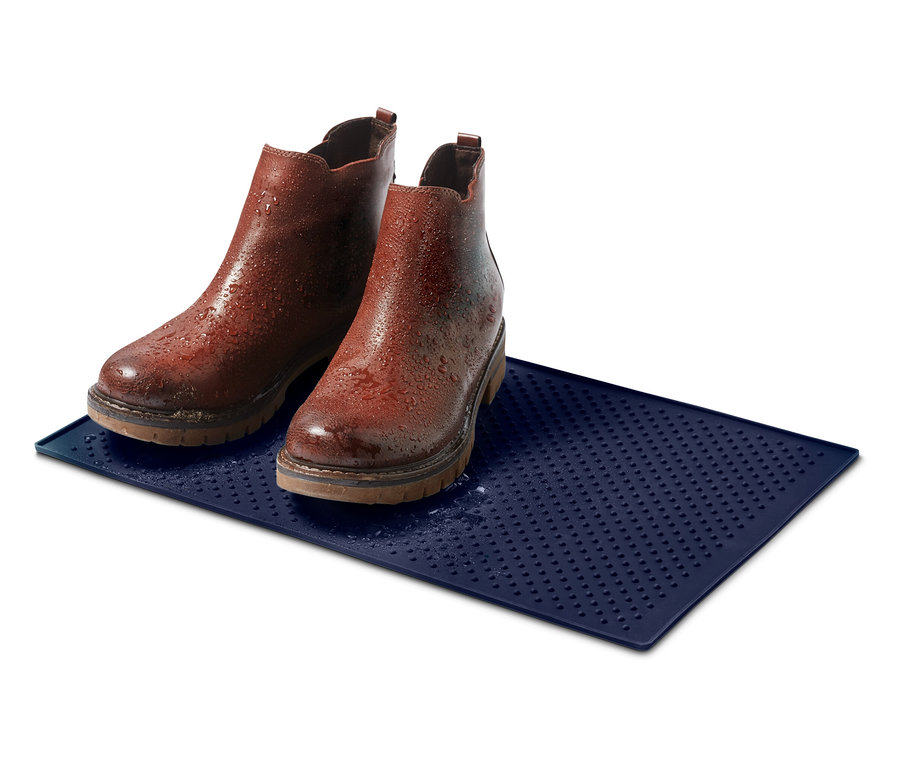 Zwei braune Lederstiefeletten stehen auf einer blauen Matte mit Wassertropfen.