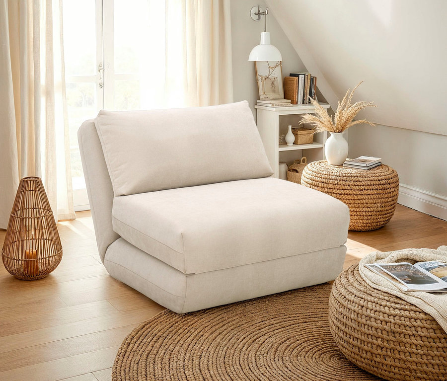 Beiger Schlafsessel mit Kissen auf einem runden Teppich. Auf dem Boden stehen ein geflochtener Hocker und eine Laterne.